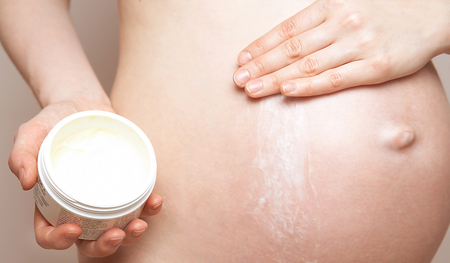 pregnant woman holding body lotion